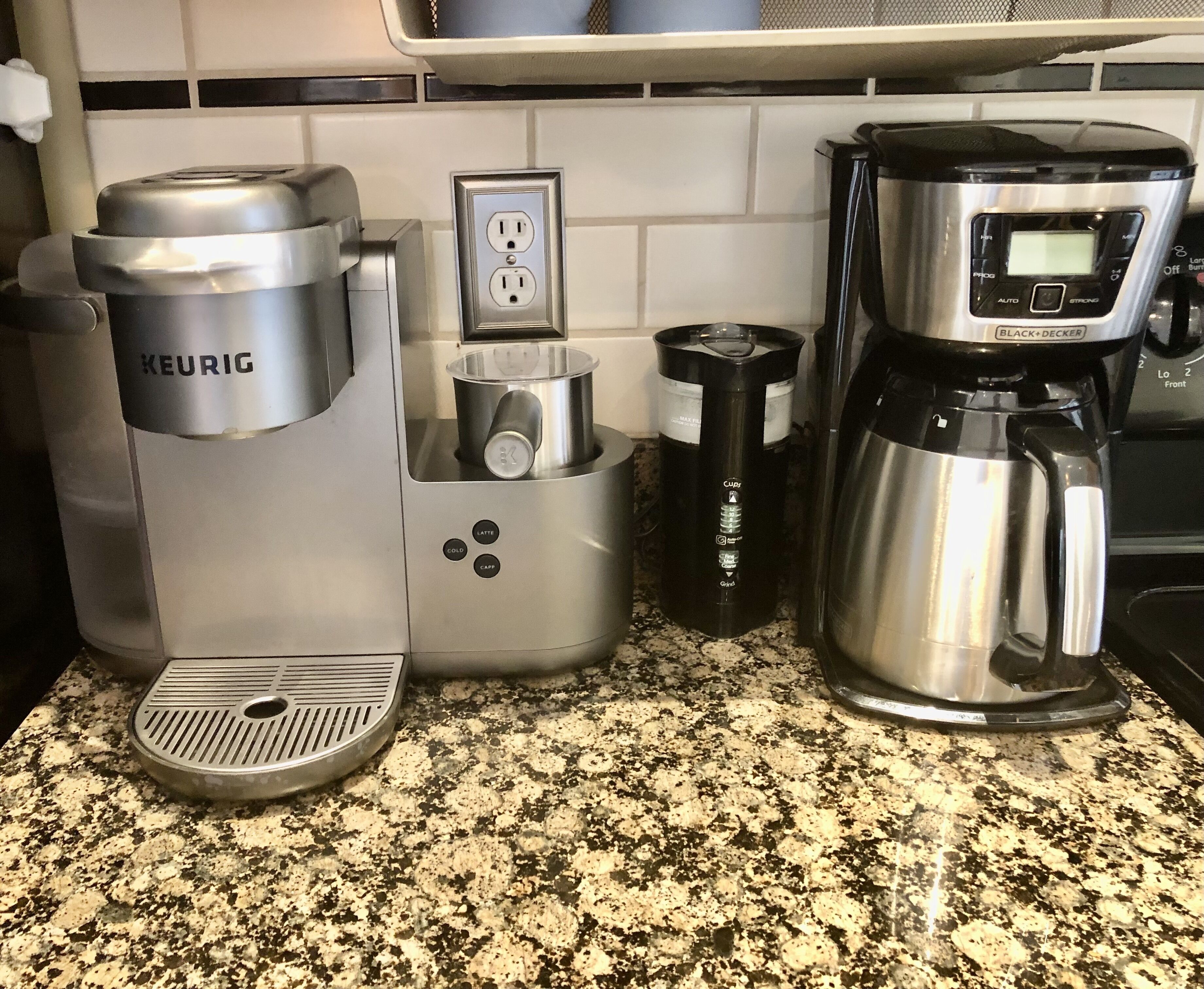 Una cafetera, un hervidor y una jarra de café sobre una encimera de granito.