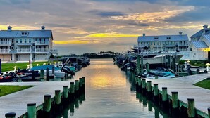Un puerto deportivo con barcos amarrados, un muelle de madera y edificios con balcones.