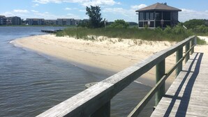 Un paseo marítimo de madera que lleva a una playa con un edificio en la arena.
