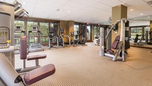 Une salle de sport équipée de divers appareils d’exercice, notamment des tapis de course, des appareils elliptiques et des appareils de musculation.