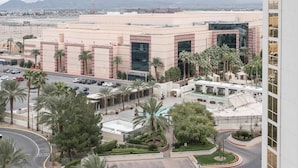 A modern hotel with a central courtyard, palm trees, and a view of distant mountains.