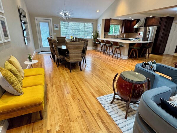 A spacious living room with a yellow sofa, a drum, and a grey armchair.