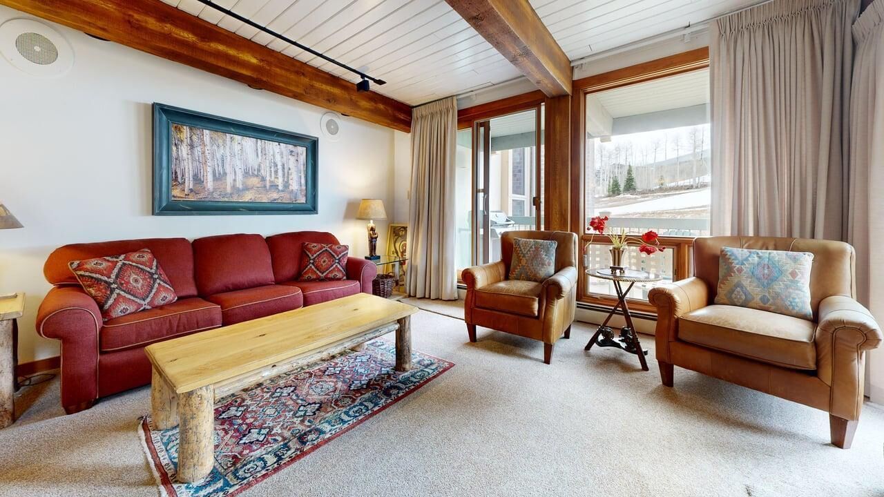 A cozy living room with a red sofa, a wooden coffee table, and two leather armchairs.