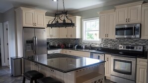 A modern kitchen with a central island, stainless steel appliances, and light-colored cabinetry.