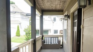 A covered porch with a bench, a doormat, and a door.