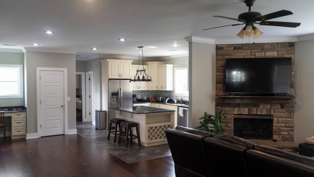 A spacious living area with a fireplace, a kitchen with modern appliances, and a large TV mounted above the fireplace.