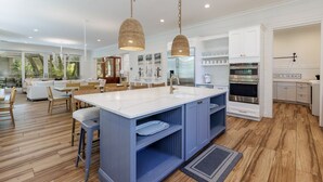 A modern kitchen with a large island, white cabinetry, and stainless steel appliances.