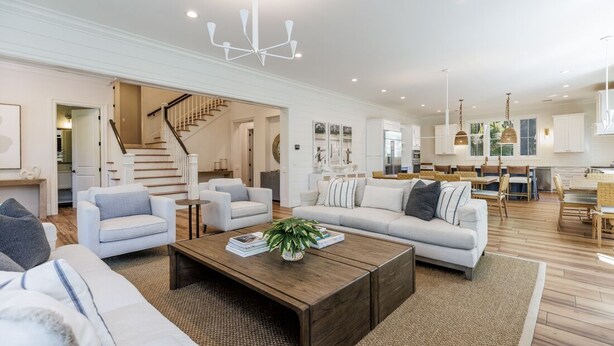 A spacious living room with a large sofa, a coffee table, and a staircase leading to another level.