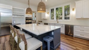 A modern kitchen with white cabinetry, a large island, and pendant lighting.