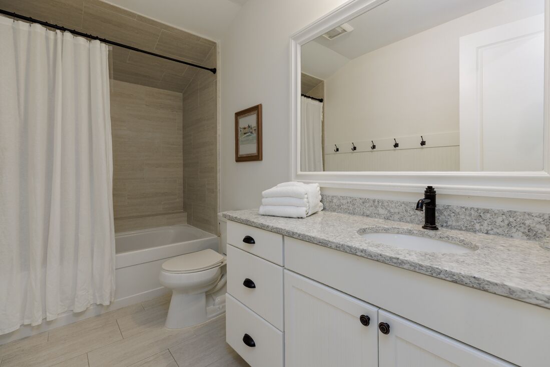 Une salle de bain avec une baignoire, des toilettes et un grand miroir au-dessus du lavabo.