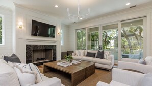 A modern living room with a fireplace, a large TV, and a comfortable seating area with a view of the outdoors.