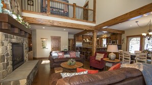 A spacious living area with a stone fireplace, leather sofas, and a dining area with wooden furniture.