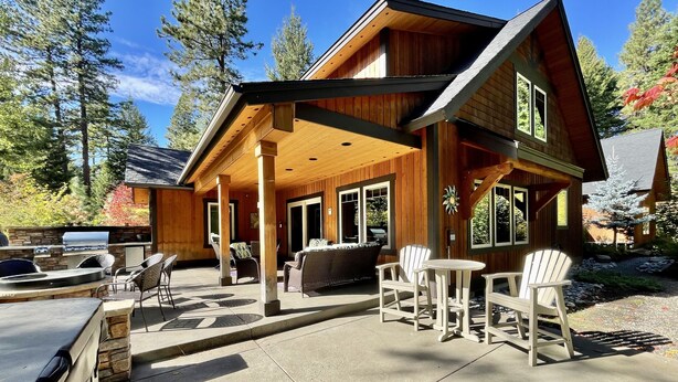 A wooden cabin with a patio area, outdoor seating, and a grill.