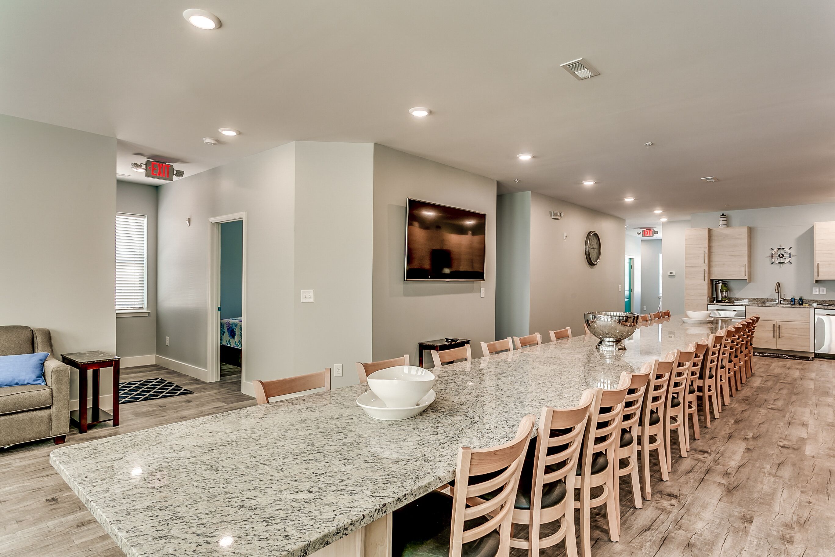 A spacious kitchen with a long granite countertop, wooden chairs, and a large island.