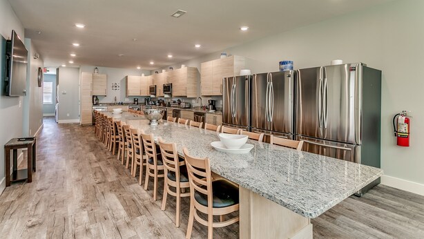 A modern kitchen with a long island, stainless steel appliances, and wooden chairs. - LARGE HOME w HUGE KITCHEN sleeps 50+huge pool+cinema+game room 1min to the SAND (North Myrtle Beach)