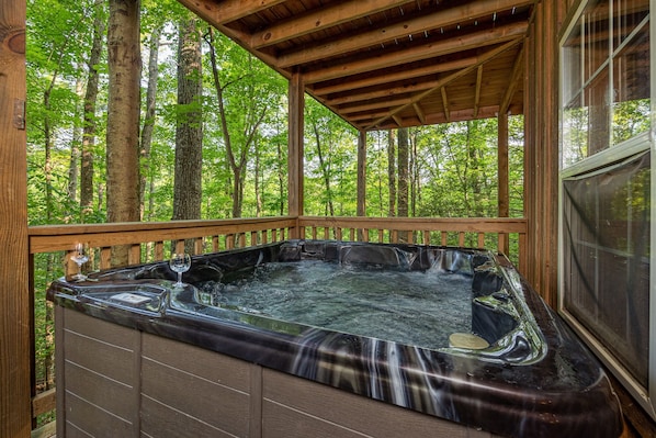 A hot tub in a wooden deck with a forest backdrop. - Perfect location, Secluded, Pet Friendly, Wooded Paradise (Sevierville)