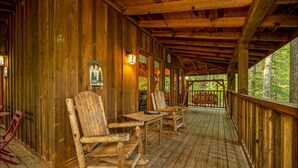 A wooden deck with rustic wooden chairs and tables, surrounded by wooden walls and a wooden railing. - Perfect location, Secluded, Pet Friendly, Wooded Paradise (Sevierville)