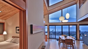 Een modern interieur met een eethoek, grote ramen en uitzicht op zee.