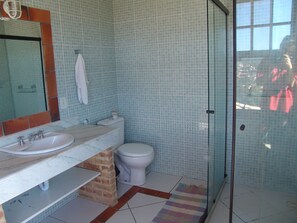 Un baño con lavamanos, inodoro y cabina de ducha de vidrio.