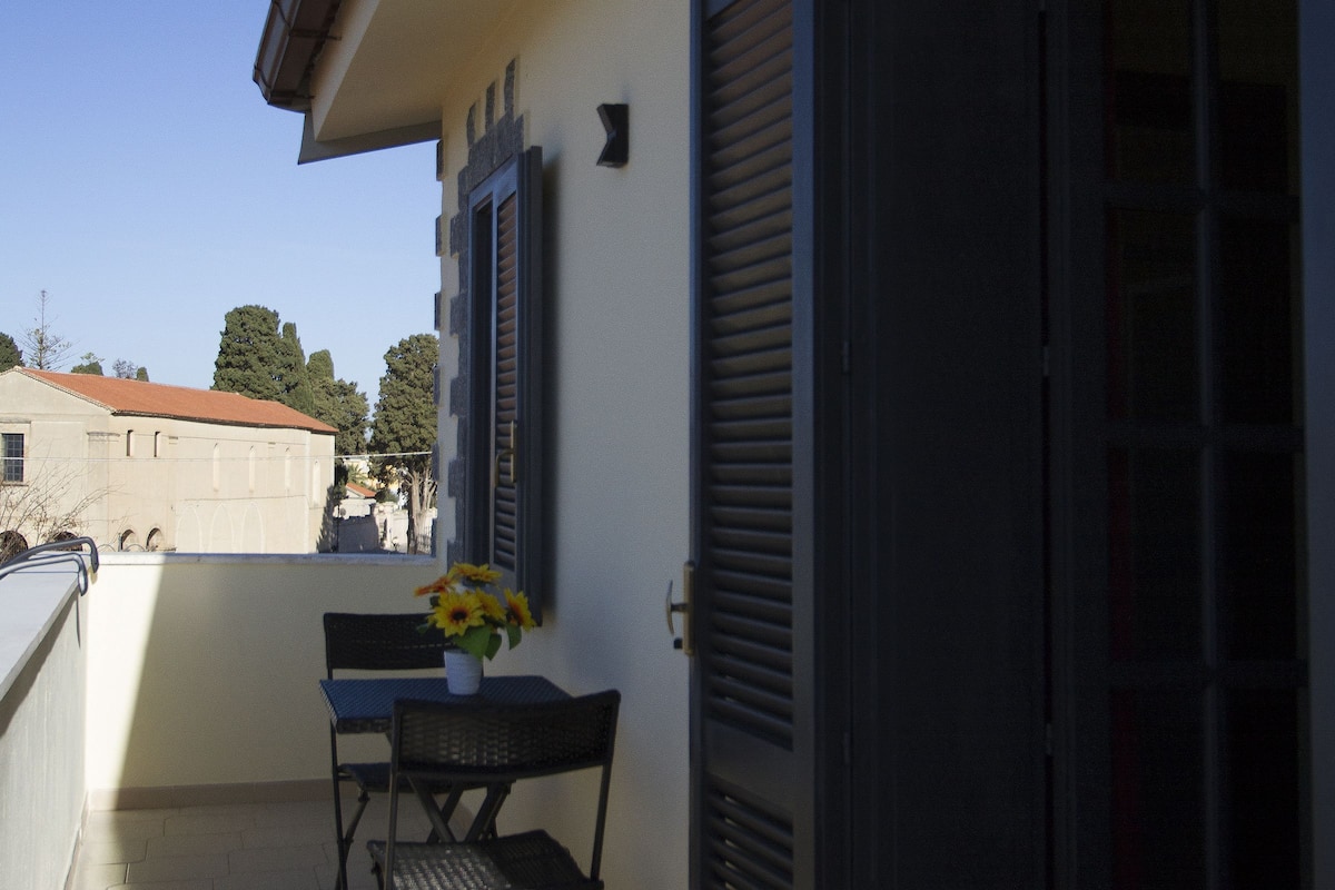 A balcony with a table and chairs, a potted plant, and a partially open door.