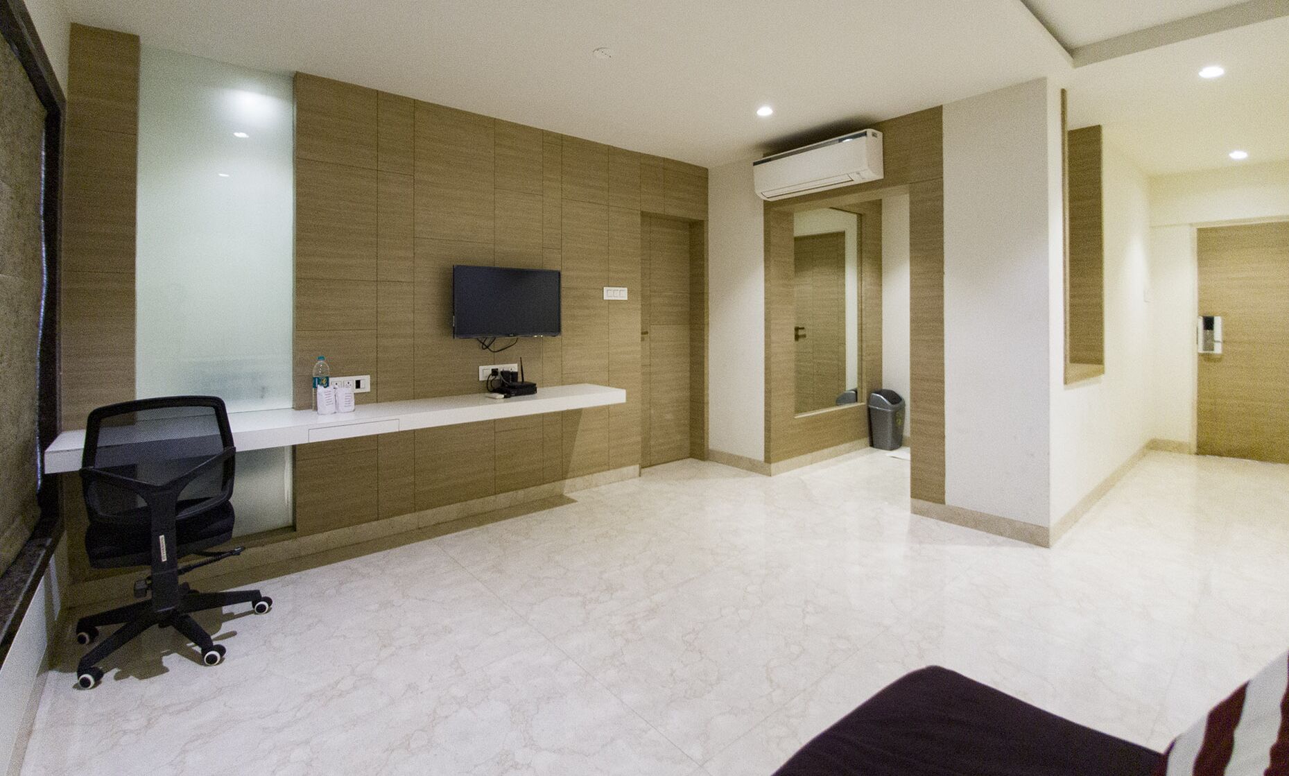 A modern reception area with a flat-screen TV, a white reception desk, and a black office chair.