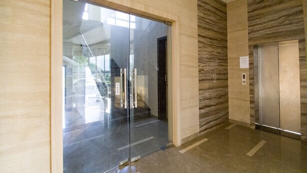 Un ascensor moderno con panel de control y puerta de cristal con botón pulsador.