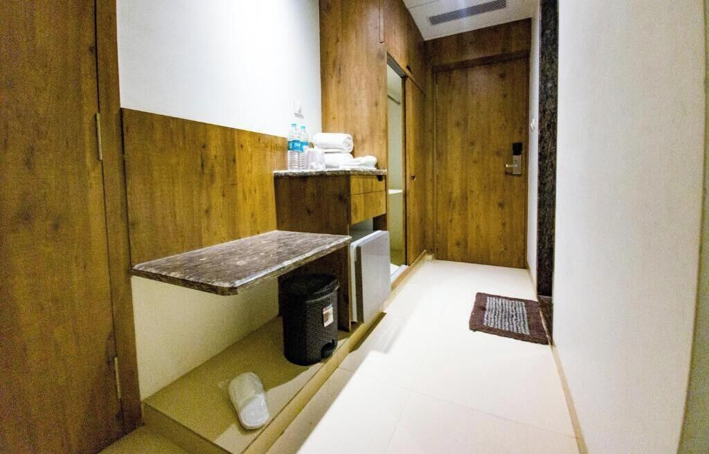 A small, compact bathroom with wooden walls, a sink, a mirror, and a towel rack.