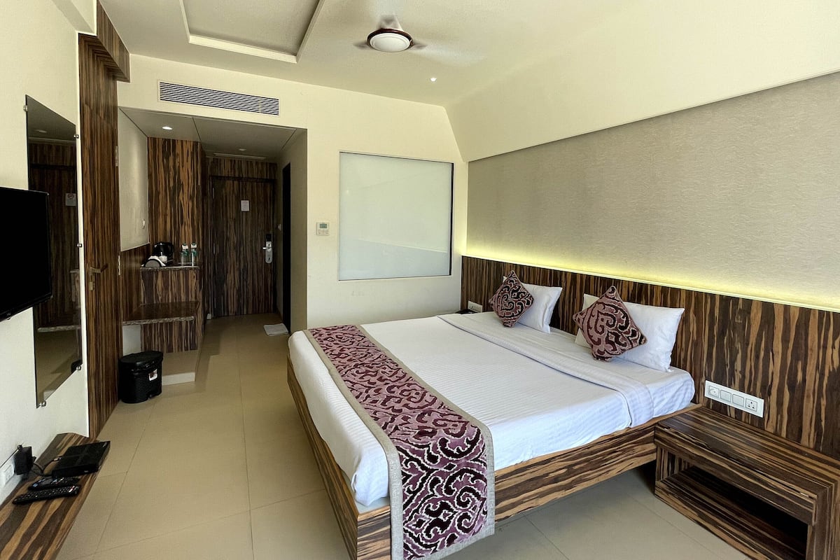 A hotel room with a bed, bedside table, TV, and a ceiling fan.