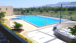 Una piscina rectangular al aire libre con agua azul cristalina, rodeada por una solería y una barandilla de metal.