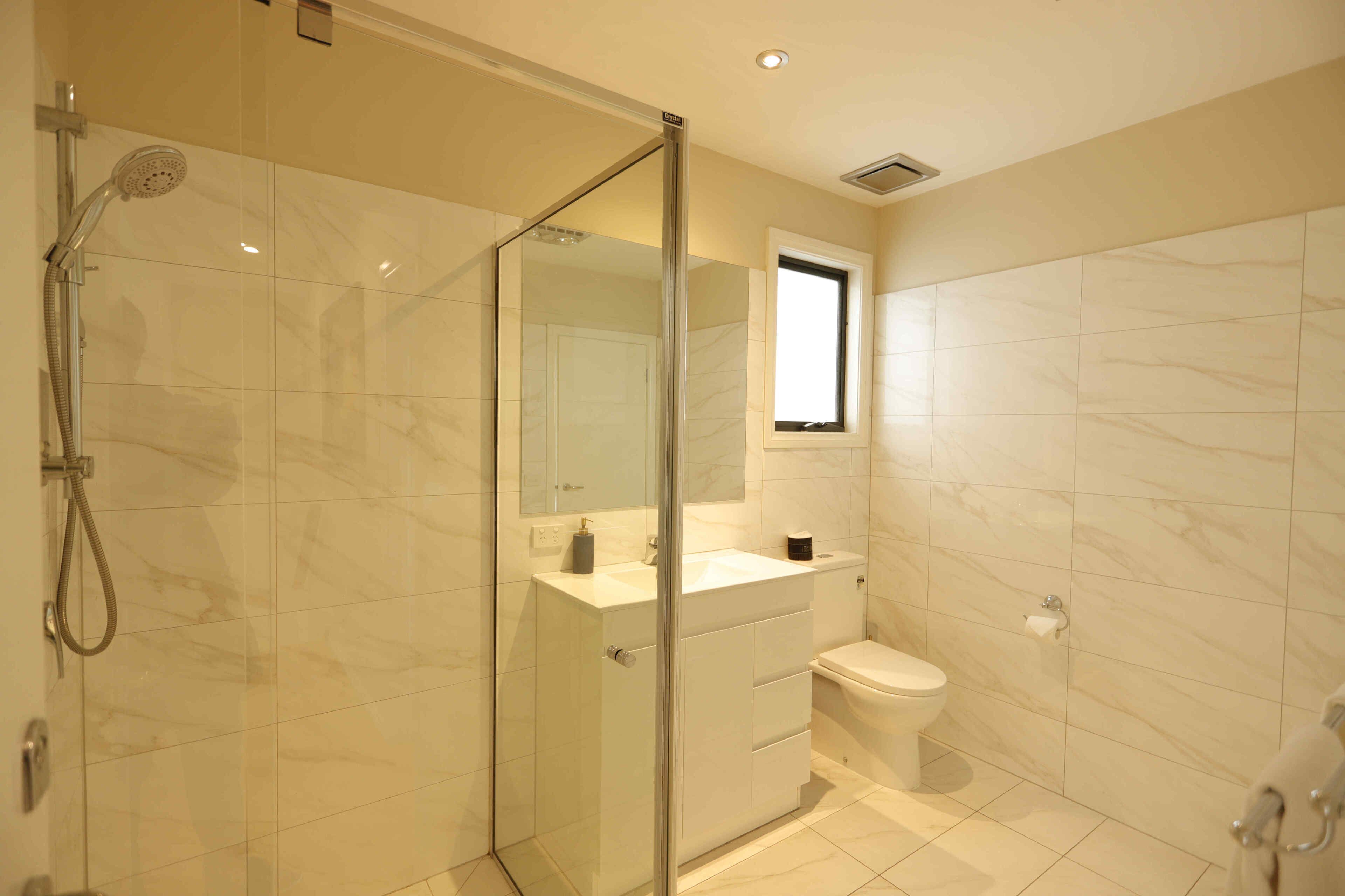 A modern bathroom with a glass shower enclosure, a white sink, and a toilet.