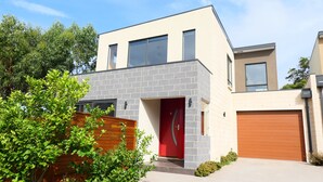 A modern two-story house with a red door, a garage, and a brick facade. - Apollo Bay Seal Apartments (Marengo)
