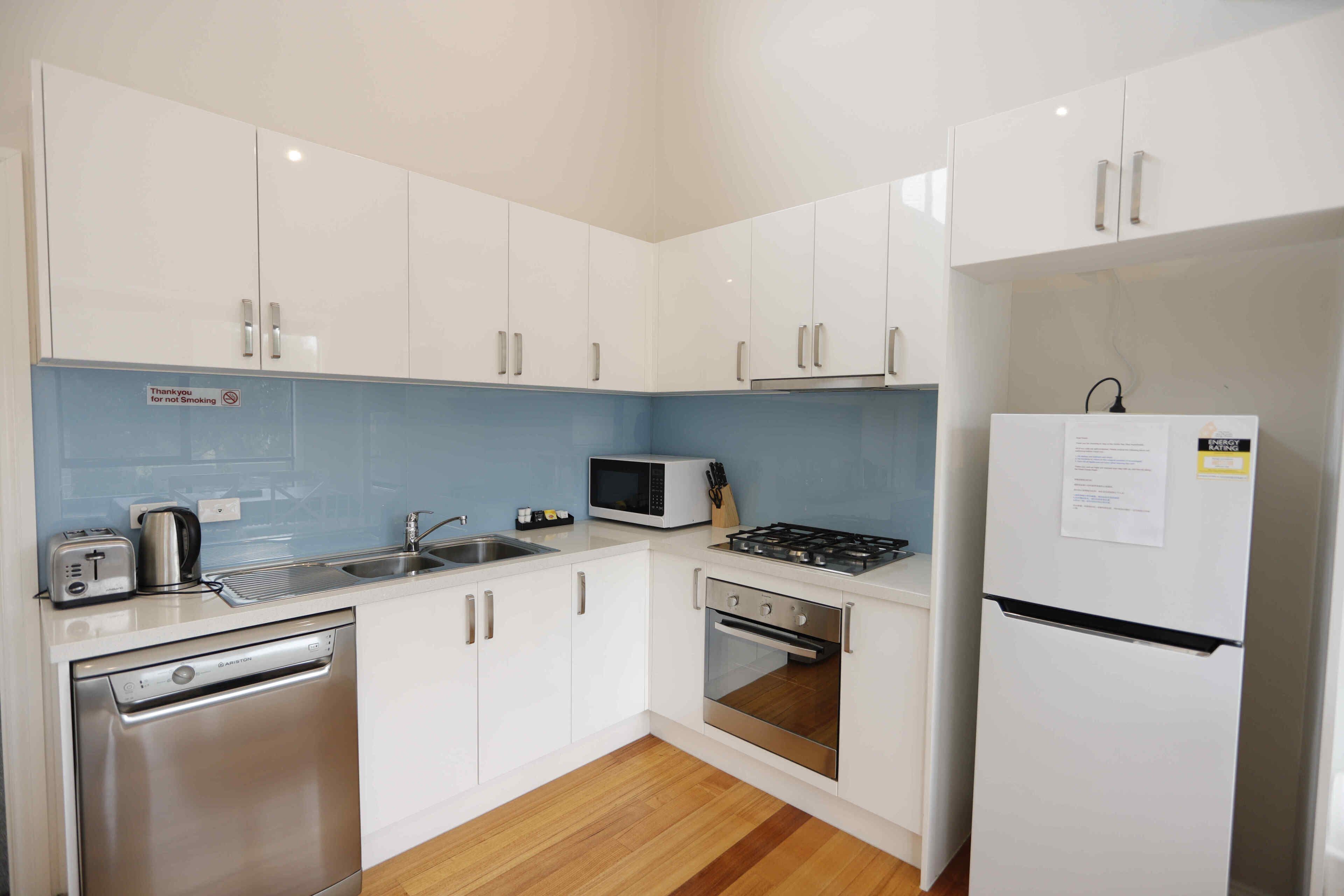 A modern kitchen with white cabinets, a microwave, a stove, a dishwasher, and a refrigerator.
