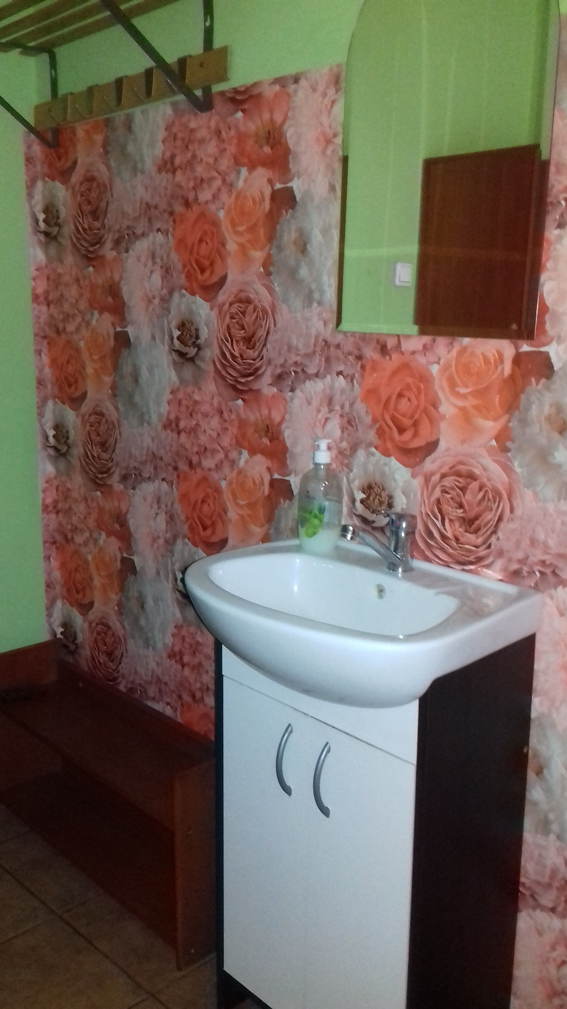 A bathroom with a sink, mirror, and floral wallpaper.