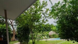 A covered outdoor area with a concrete floor, stone steps leading to a pool, and a large bowl with shells.