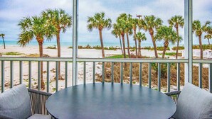 A balcony with a view of a beach, palm trees, and the ocean.