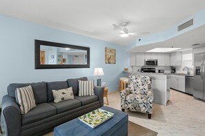 Una sala de estar con un sofá, un sillón y una mesa de centro con una bandeja con estampado de cactus.