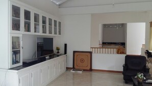 A living room with a TV, bookshelves, a fireplace, and a staircase. - White House (Ragama)