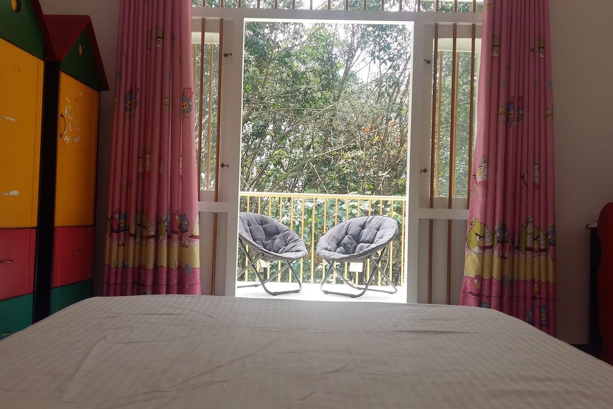 Ein Schlafzimmer mit einem Bett, zwei Stühlen, einem Balkon mit Geländer und farbenfrohen Schließfächern.