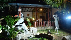 Un espace extérieur rustique agrémenté d’une fontaine en pierre, de statues et d’une structure en bois.