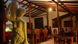 Une pièce avec un plafond en bois, une statue, ainsi que plusieurs chaises et tables en bois.