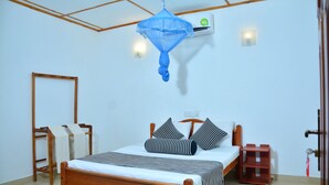 Une chambre à coucher avec un lit en bois, une moustiquaire, une table de chevet et un climatiseur fixé au mur.