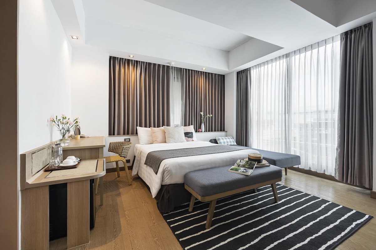 Una habitación de hotel moderna con una cama grande, un escritorio y un banco.