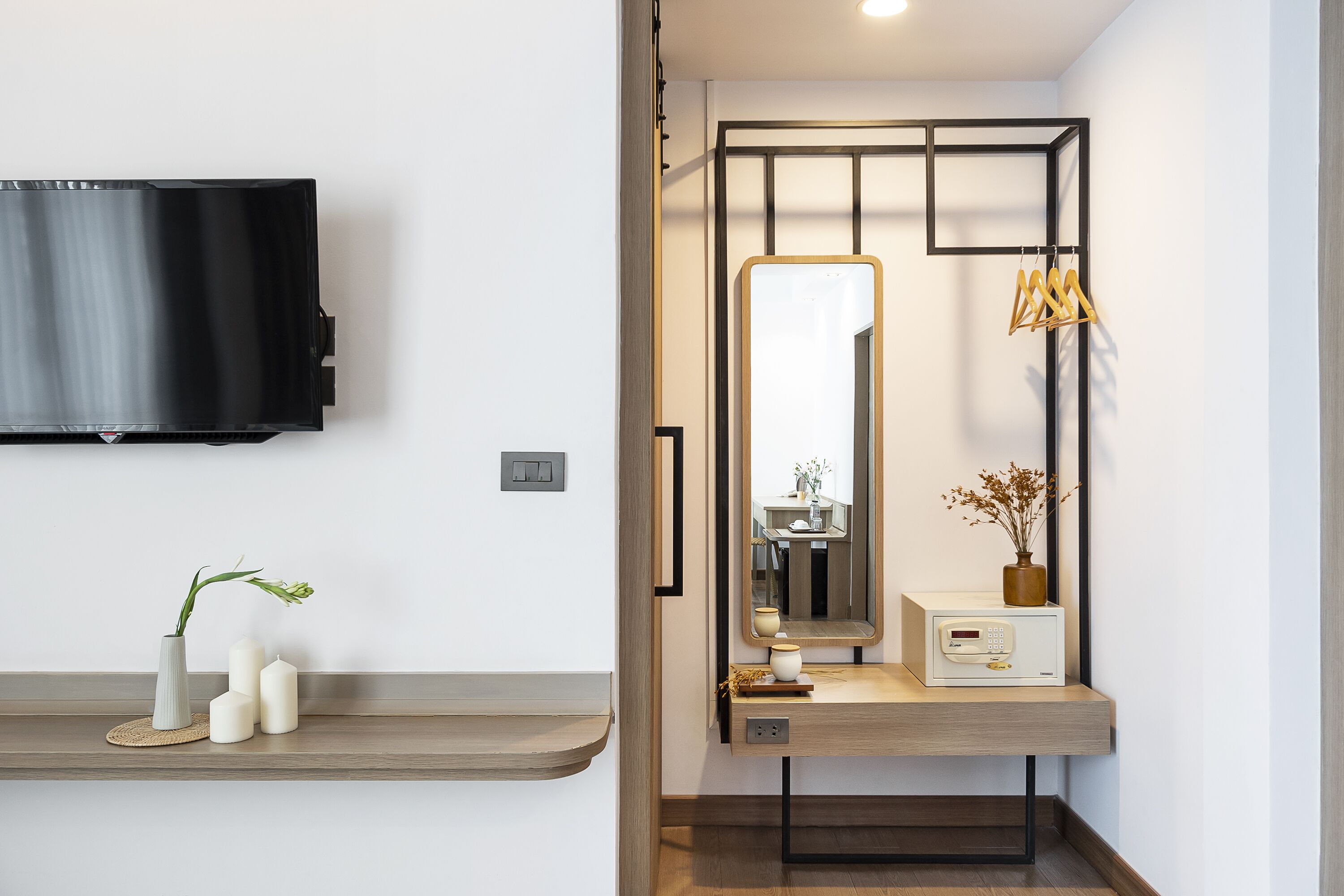 A modern bathroom with a vanity, a mirror, a television mounted on the wall, and a small shelf with decorative items.