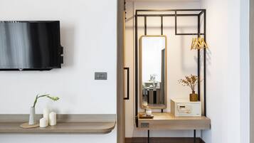 A modern bathroom with a vanity, a mirror, a television mounted on the wall, and a small shelf with decorative items.