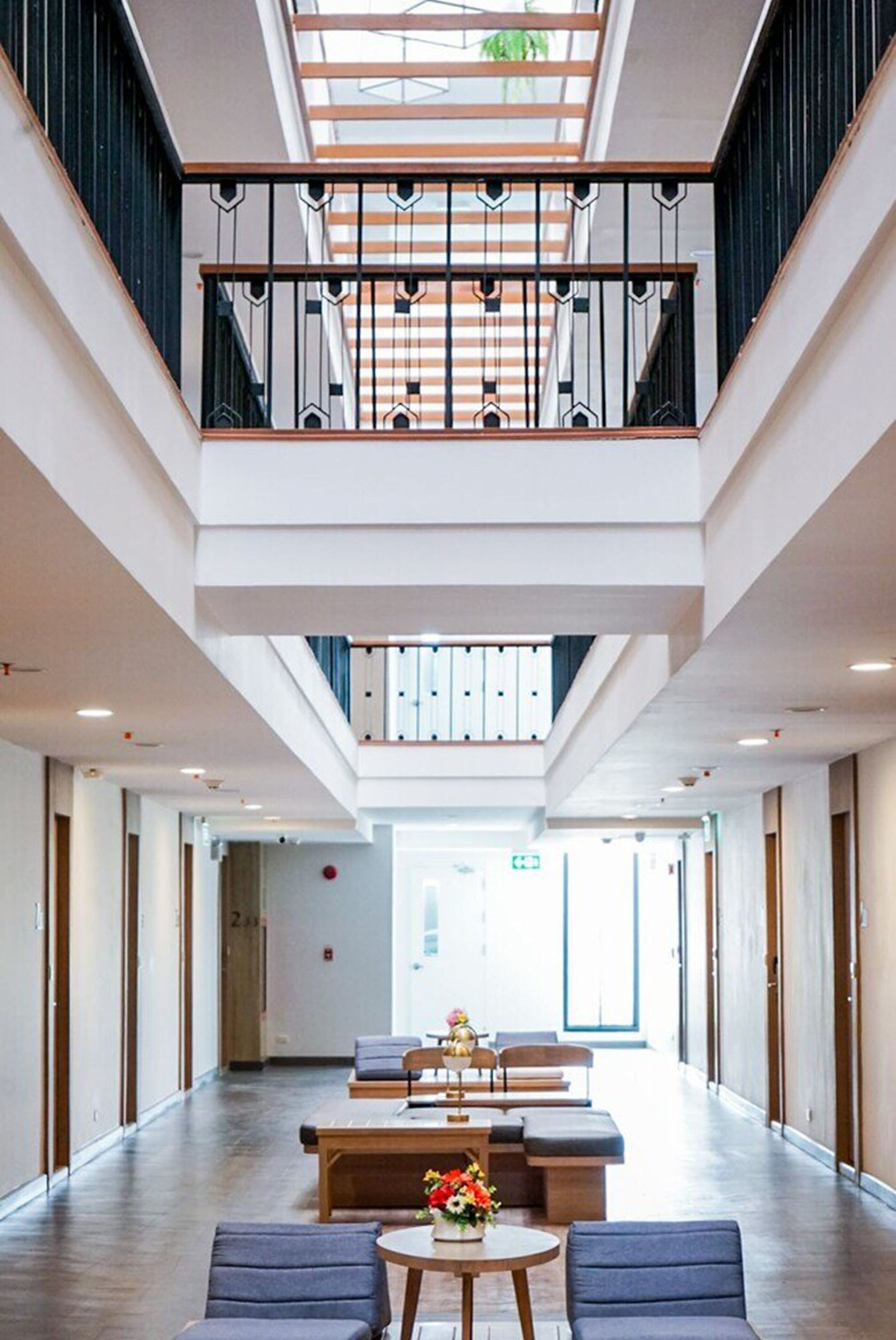A spacious lobby with a high ceiling, a mezzanine level, and a central seating area with tables and chairs.