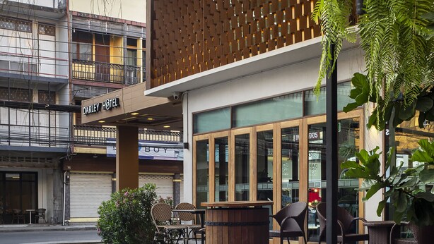 Un hôtel au design moderne, doté d’une façade en bois, d’un espace extérieur aménagé et de grandes fenêtres.