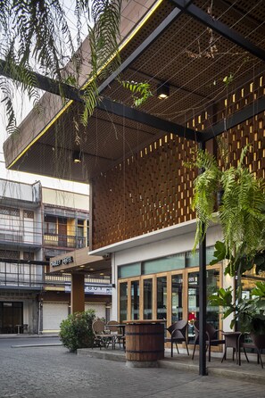A hotel with a modern design, featuring a wooden facade, outdoor seating area, and large windows. - Darley Hotel Chiangmai (Chiang Mai)