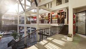 Un atrium à plusieurs niveaux, doté d’un escalier, de rampes en verre et offrant une vue sur la rue.