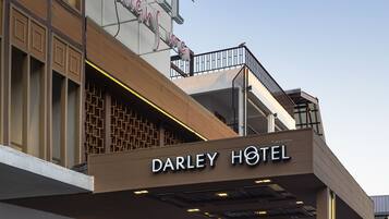 Exterior del Hotel Darley, con fachada moderna, zona de acceso cubierta y un letrero que indica una calificación de 5 estrellas.