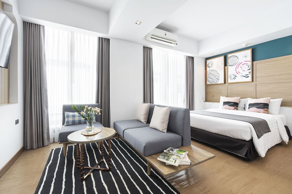 Una habitación de hotel moderna con sofá, cama, mesita de centro y vistas a la ciudad.